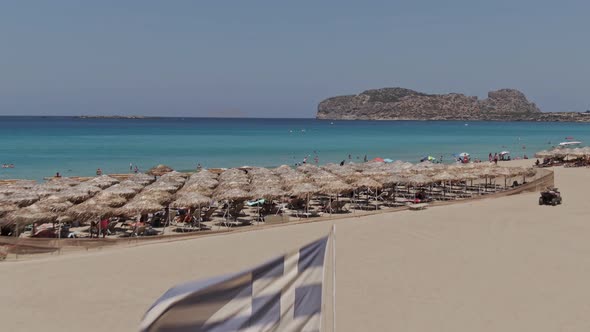 Flag of Greece wawing sandy coast of Falasarna beach in Crete island, drone ascend view alt