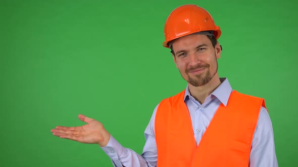 A Young Handsome Construction Worker Presents Something To the Camera - Green Screen Studio alt
