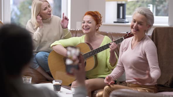 Three Talented Adult Caucasian Women Playing Guitar Singing As Friend Recording Video for Social alt