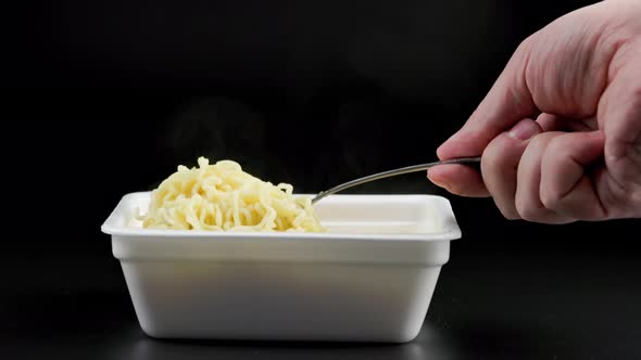 Hand with Fork Stirring Cooked Instant Noodles From Styrofoam Container