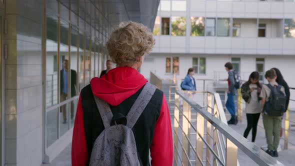 Follow Shot of Teen Schoolboy with Backpack Walking Outdoors alt