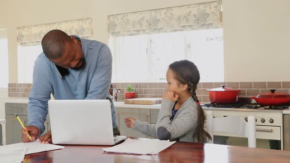 Father talking on mobile phone while daughter sitting beside in kitchen 4k alt