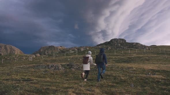 Young Loving Couple Running in Field on Background of Epic Dramatic Clouds Slow Motion