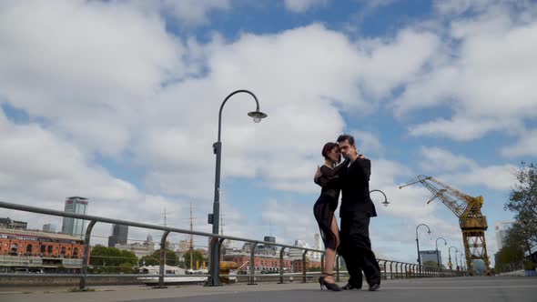 Intimate couple of dancers performing tango routine in Puerto Madero promenade alt