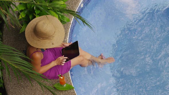 Woman sitting on edge of hot tub using digital tablet. Shot on RED EPIC for high quality 4K, UHD, Ul alt