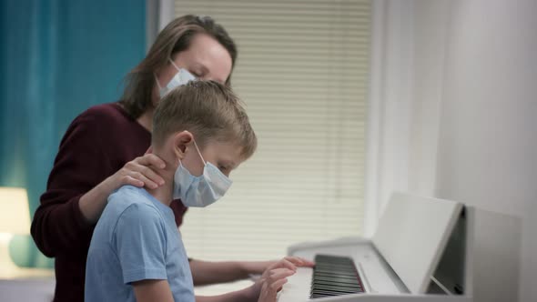 Closeup Filming of a Mom Bracing Up Her Boy To Learn Playing Tunes on the Piano By Patting His Head