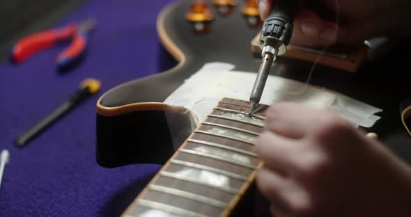 Luthier Heats Frets on Guitar By Soldering Iron Before Refretting Preparations for Frets Replacement alt