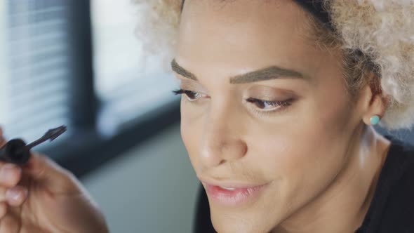 Transgender Woman Smiling As She Puts Mascara on alt
