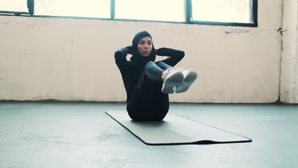 A focused arabian sports woman wearing a national hijab is pumping press alt