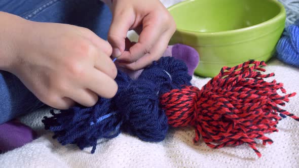 Girls making dolls from strings.