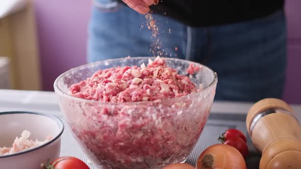 Adding Salt and Spices to Minced Meat with Onion and Spices in a Glass Bowl Making Cutlets alt