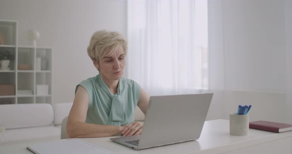 Middle-aged Woman Is Talking Online By Video Call on Notebook, Sitting at Home, Modern Technology alt