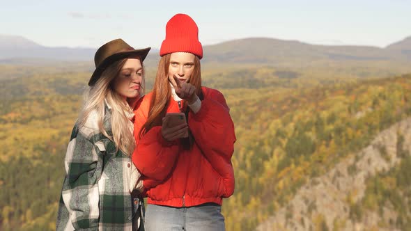 Two Attractive Girls Tourists Standing on a Hill Lay a Further Route on Smartphone