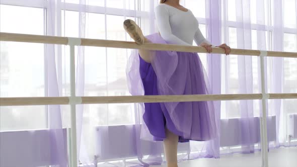 Professional Ballerina is Puts Her Leg on the Barre Stand