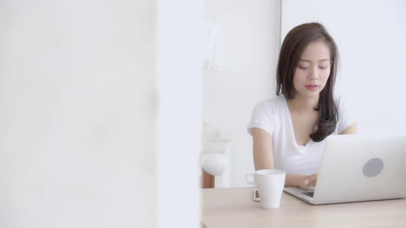Beautiful young freelance asian woman smiling working and typing on laptop computer job at desk. alt