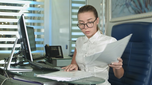 Hard working businesswoman with laptop and paperwork alt