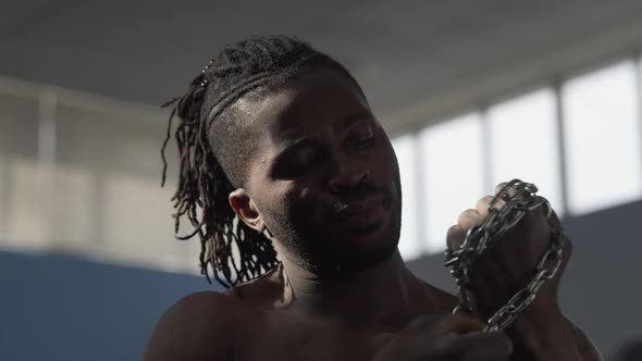 Headshot of Confident Serious African American Man Wrapping Metal Chain on Fist Looking at Camera alt