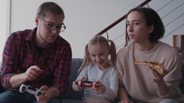 Father, Mother and Little Girl Play at Video Games at Home