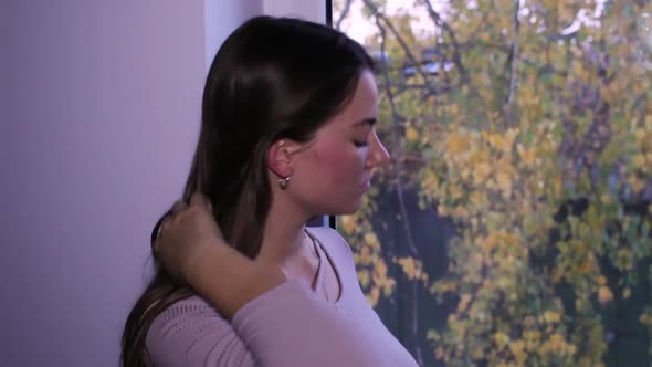 Beautiful teenage girl standing next to a window, daydreaming alt