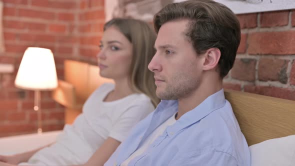 Portrait of Young Couple Smiling at Camera From Bed alt