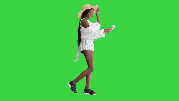 Smiling African American Woman in a Straw Hat Taking Selfie While Walking on a Green Screen, Chroma alt
