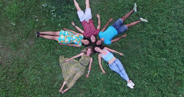 Aerial of group of friends forming a star shape lying in grass alt