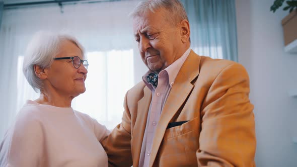 Happy Elderly Couple Dancing at Home in Formal Wear alt