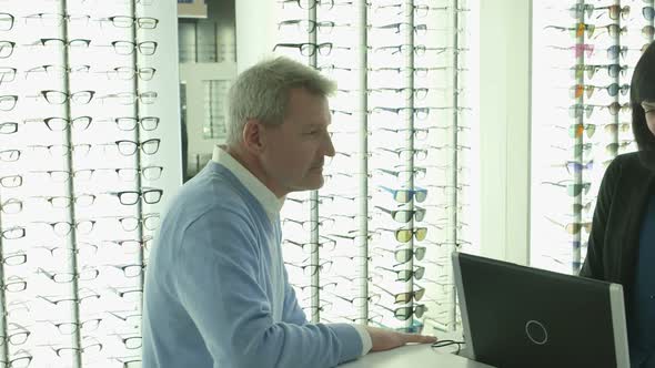 Male Patient purchases a new pair of glasses with the assistance of the Female Optician