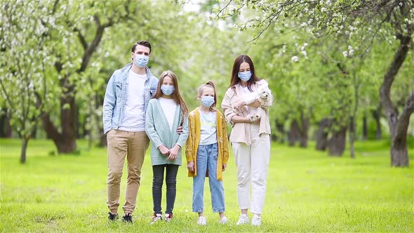 Adorable Family in Blooming Cherry Garden in Masks