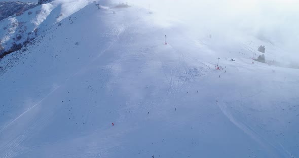 Side Aerial Over Winter Snowy Mountain Top Ski Tracks Resort with Skier People Skiing