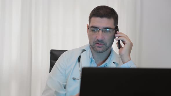 Male Doctor Talking On The Phone Inside His Clinic. medium shot alt