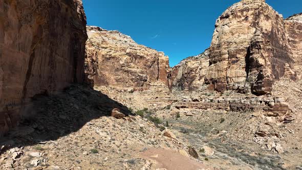 Flying along rocky wall cliff in the Utah desert moving up canyon alt