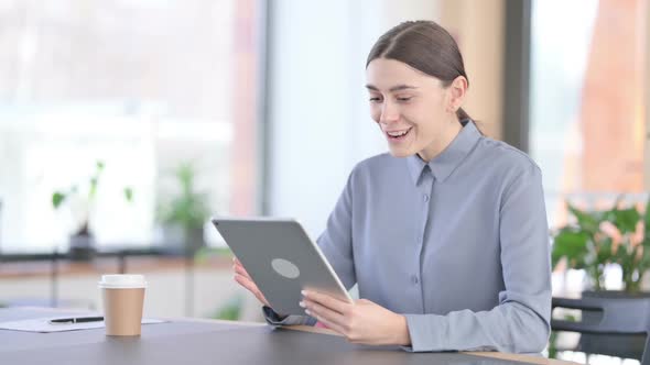 Successful Young Latin Woman Celebrating on Tablet at Work alt