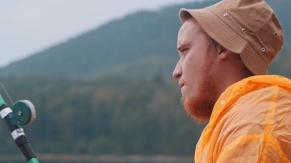 Lonely Man Sitting on a Shore and Fishing - Looking at a Hook with a Bait alt