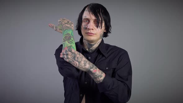 Portrait of Confident Man with Tattooed Face Showing Tattoos on Hands Looking at Camera alt