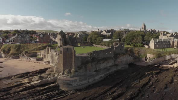 Aerial drone view orbiting the shoreline around St Andrews Castle in Scotland, UK. View toward cathe alt