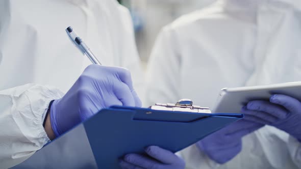 Two technicians making notes in protective gloves. Shot with RED helium camera in 8K. alt