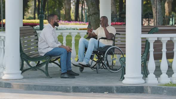 Mature Black Man and His Young African Male Friend Sitting Outdoors Talking Discussing Perspectives alt