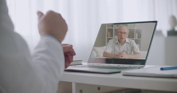 Doctor Is Explaining Treatments To Elderly Patient During Online Consultation By Internet, Closeup alt