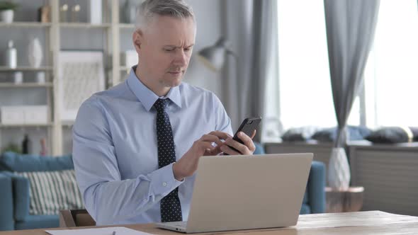 Gray Hair Businessman Using Smartphone at Workplace alt