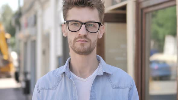 Serious Young Man Standing Outdoor along Road alt