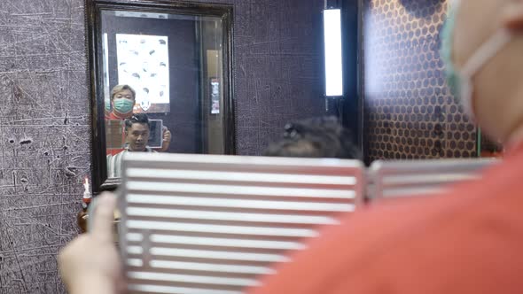 A Commercial Video of a Barber Holding a Mirror to Show the Haircut to a Client in a Barber Shop alt