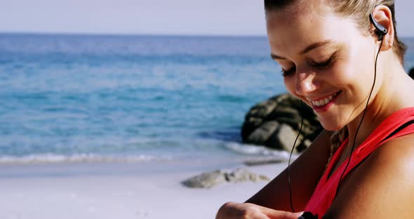 Fit woman putting music on mobile phone before jogging alt