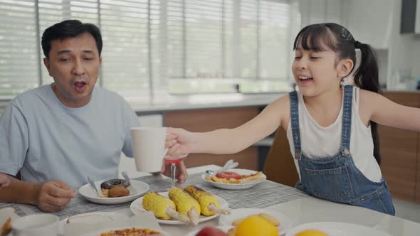  Cheerful young asian parents and cute small kids enjoy breakfast together  alt