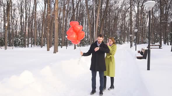 Young Woman Sneaks Up Behind the Man and Closes His Eyes. Romantic Date in the Open Air in the Park alt