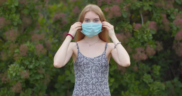 Beautiful young girl, blonde puts on a medical mask.