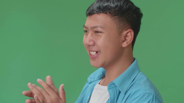 Side View Of Young Asian Man Clapping Her Hands In The Green Screen Studio alt