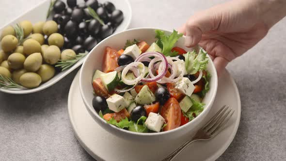 The man picks up a plate of salad and then puts it back on the table	