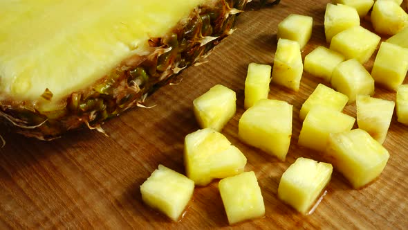 Pieces of pineapple on a cutting wooden board. alt