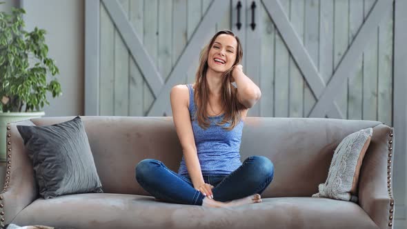 Adorable Playful Girl Sitting on Couch Laughing Relaxing at Home alt